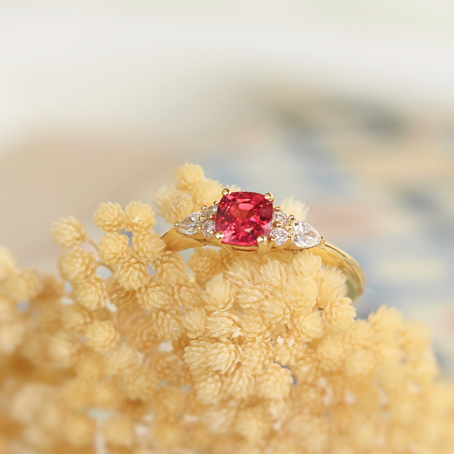 bague de fiançailles ornée d'un superbe spinelle rose intense épaulé de diamants sur une monture en or jaune 18K