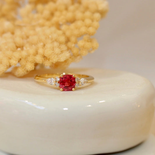 Bague de fiançailles ornée d'un spinelle de couleur rose intense et de deux diamants taille poire sur une monture en or jaune