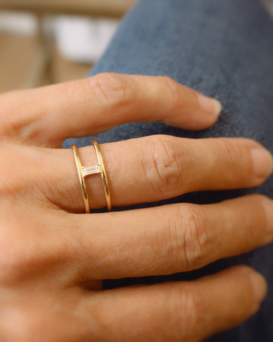 bague composée de deux anneaux en or jaune avec au centre un diamant taille baguette