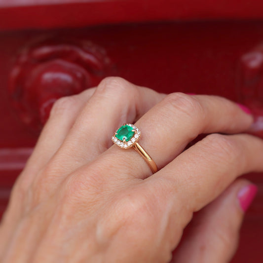 bague de fiançailles émeraude entourage diamants sur une montute en or rose