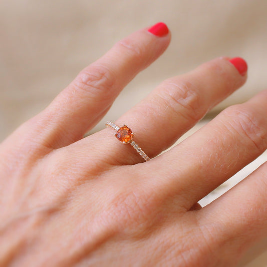 bague délicate avec au centre un saphir orange intense épaulé de chaque coté par une ligne de diamants sertis sur l'anneau