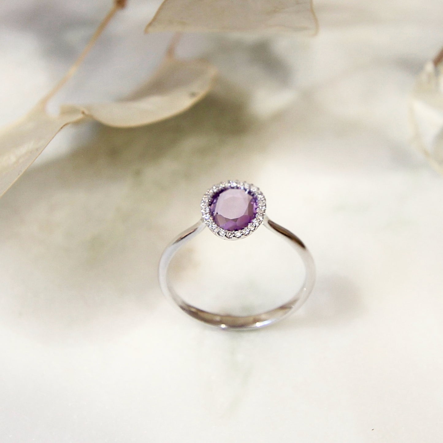 bague moderne et fine ornée d'une améthyste entourée de diamants sur une monture en or blanc