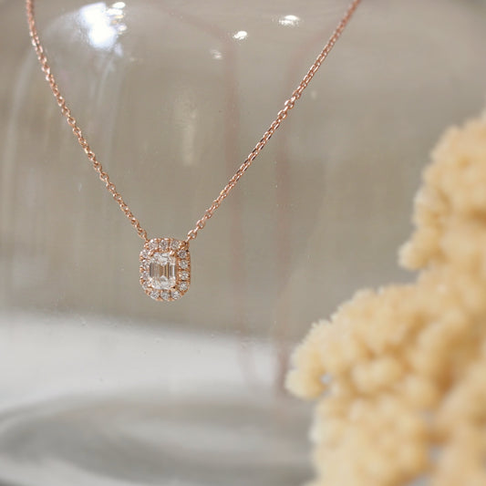 Collier pendentif avec un diamant taille émeraude et un entourage de diamants taille brillant. monture en or rose 18k
