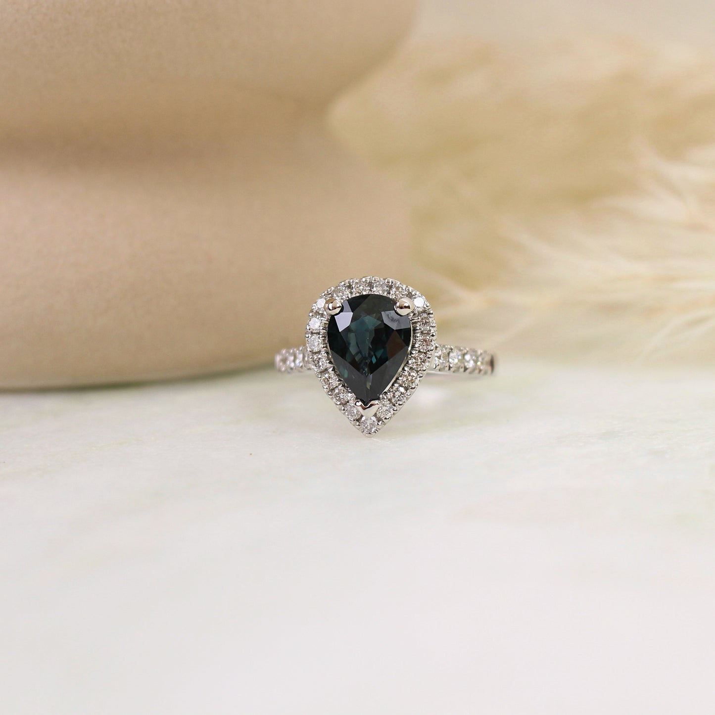 superbe bague de fiancaille unique ornée d'un saphir vert foret et de son entourage diamanté. La pierre centrale est taillé en poire