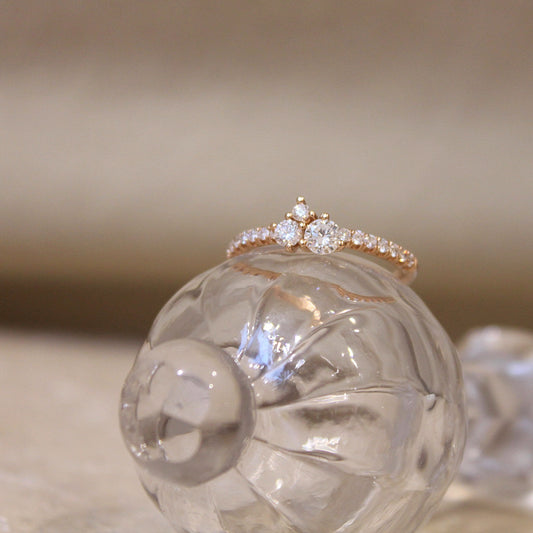 bague ornée d'un trio de diamants taille brillant avec une monture en or rose et l'anneau est aussi serti de diamants