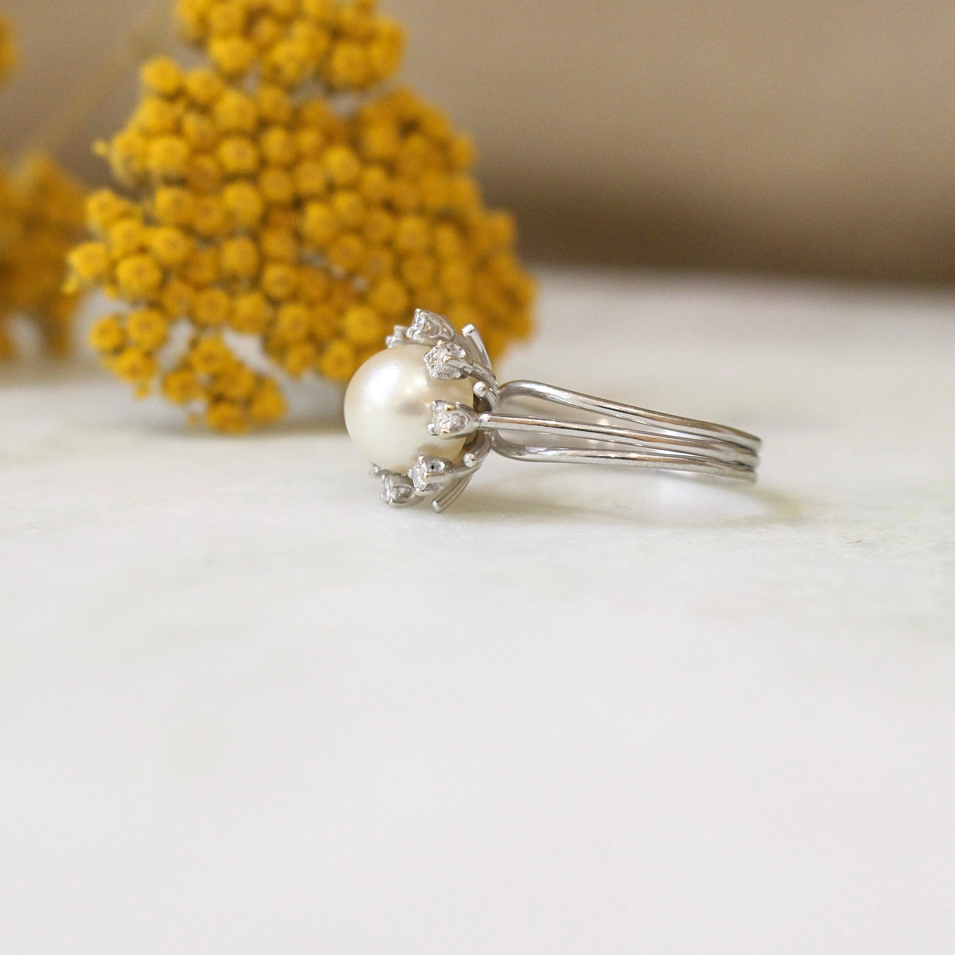bague vintage des années 70 forme marguerite ornée d une perle de culture avec un entourage de diamants-monture en or blanc 18k