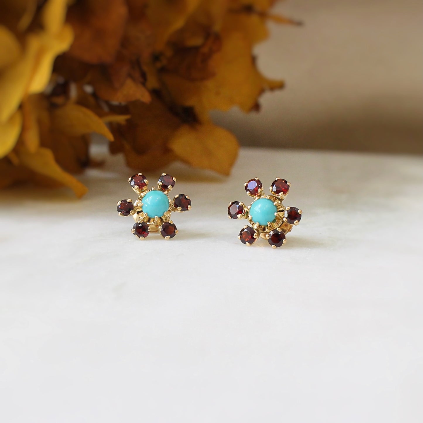 boucles d oreilles pour femme avec au centre un cabochon de turquoise véritable et un entourage de grenats en serti griffes-puces d oreilles vintage formant une fleur sur une monture en or jaune 18K