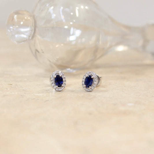 Petites boucles d'oreilles pour femme ornées de saphirs taille ovale avec un entourage de diamants sur une monture en or blanc 18k