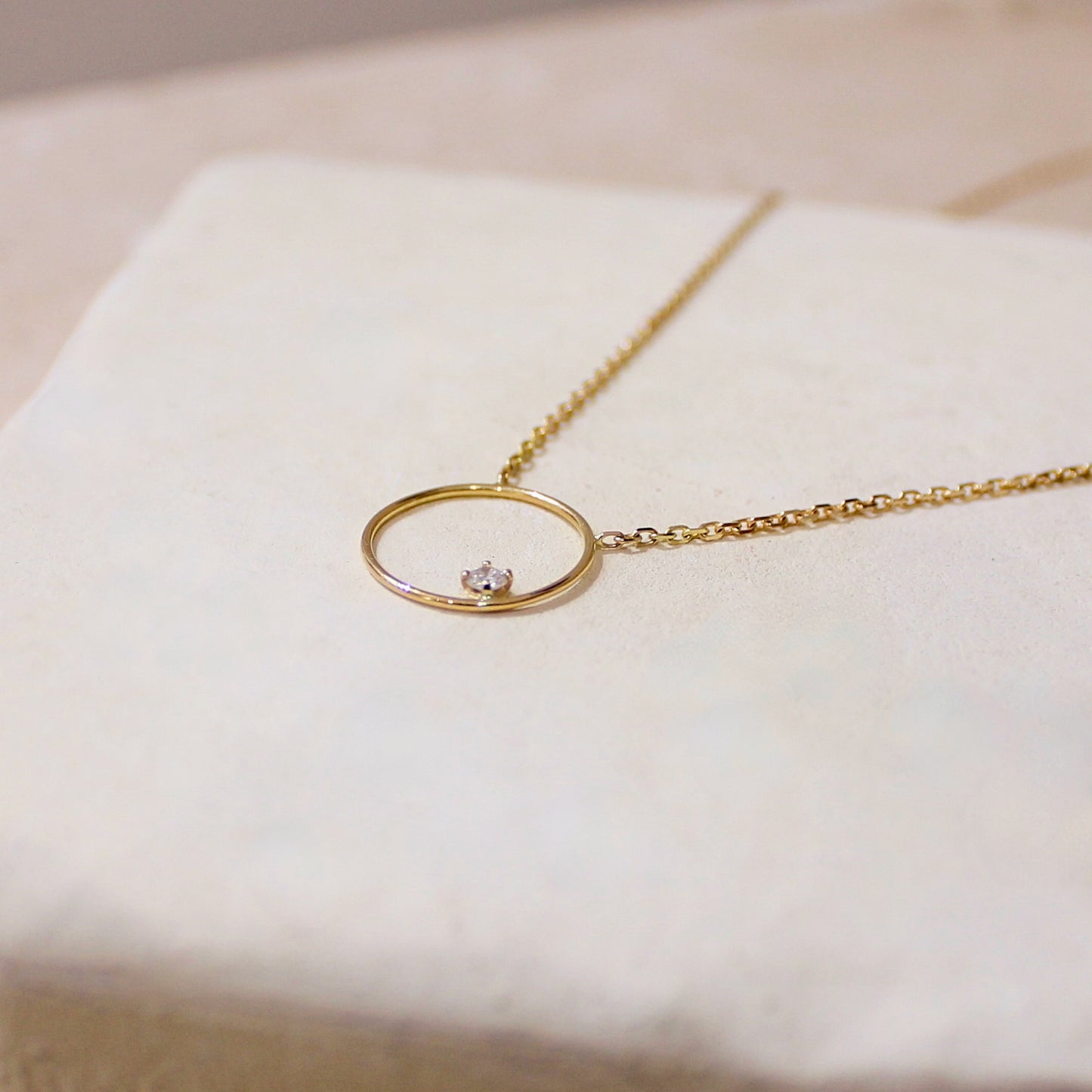 un diamant serti sur un cercle en or jaune pour ce collier fin élégant
