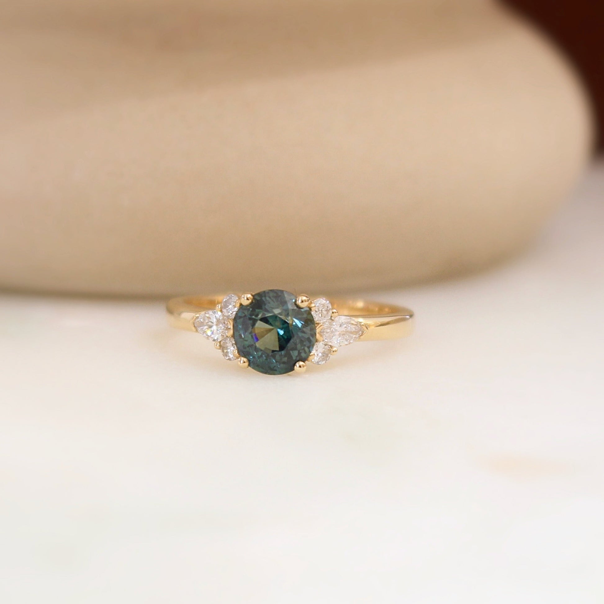 bague de demande en mariage avec au centre un saphir teal et des diamants taille navette et ronds