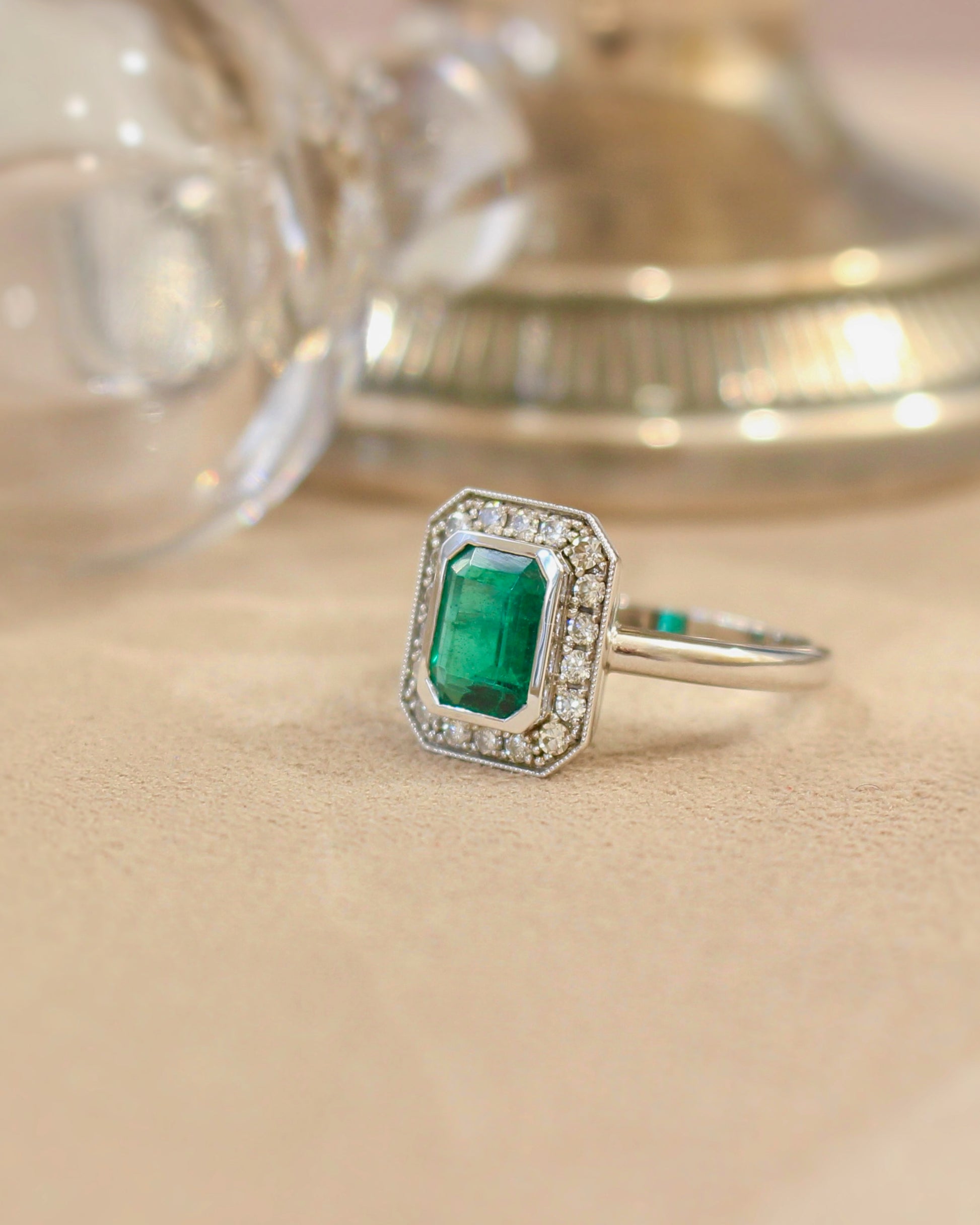 bague émeraude taille rectangle et un entourage de diamants- sertissage finition perlée. monture en or blanc