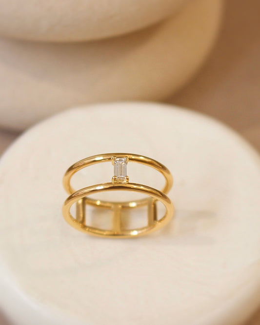 bague pour femme style moderne avec au centre un diamant taille baguette serti sur Deux anneaux en or jaune18k