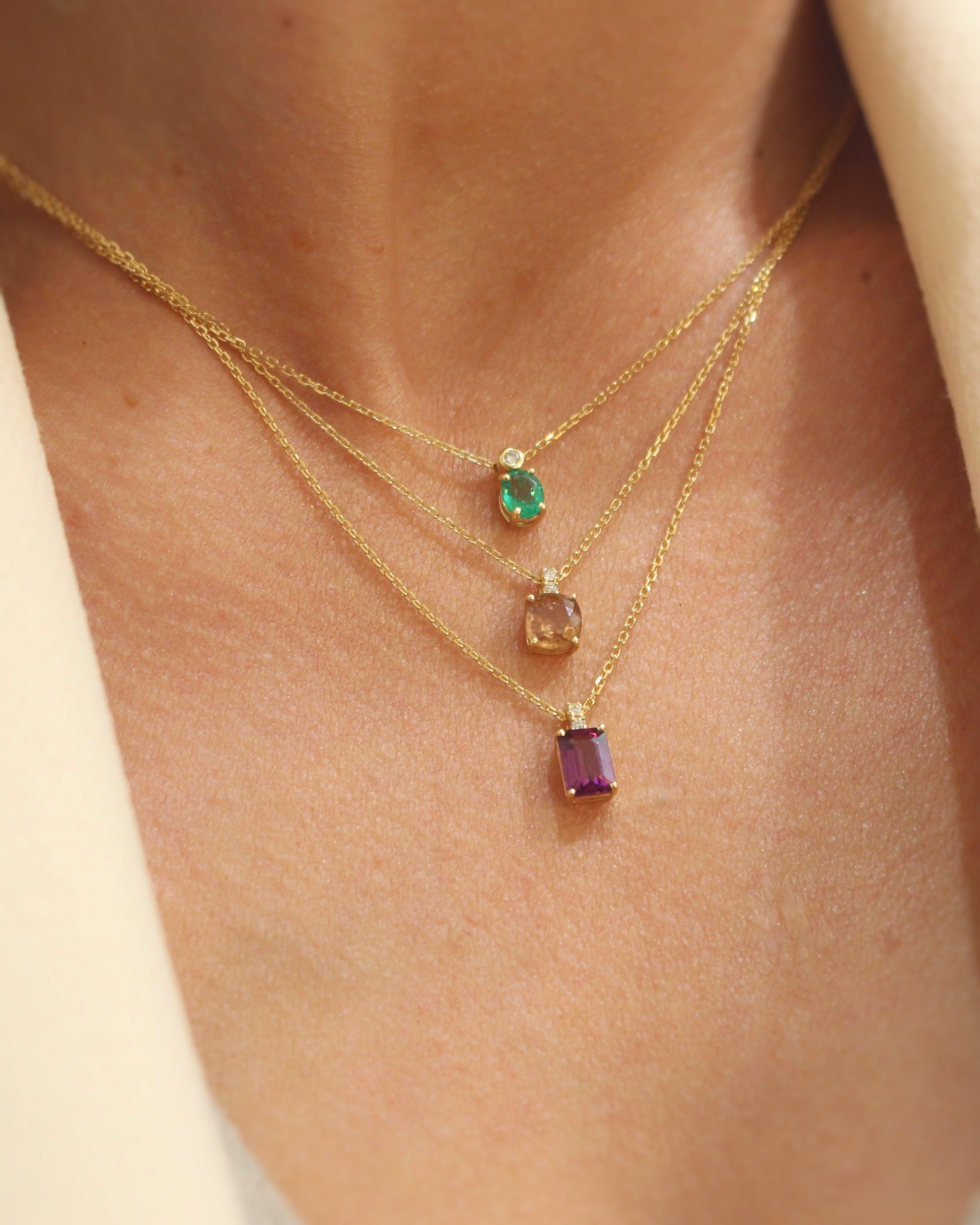 3 colliers avec pendentifs pierres précieuses et diamants : émeraude, grenat et combolite sur chaine en or jaune 18k