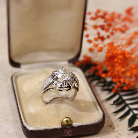 Superbe solitaire diamant, vers 1960, une monture remarquablement travaillée, en or blanc serti platine. Pierre centrale taille ancienne de 1,60 carat. Pierres : Diamant taille ancienne de 1,60 carat en serti platine doubles griffes, épaulé de chaque coté par trois diamants taille ancienne en serti grain.