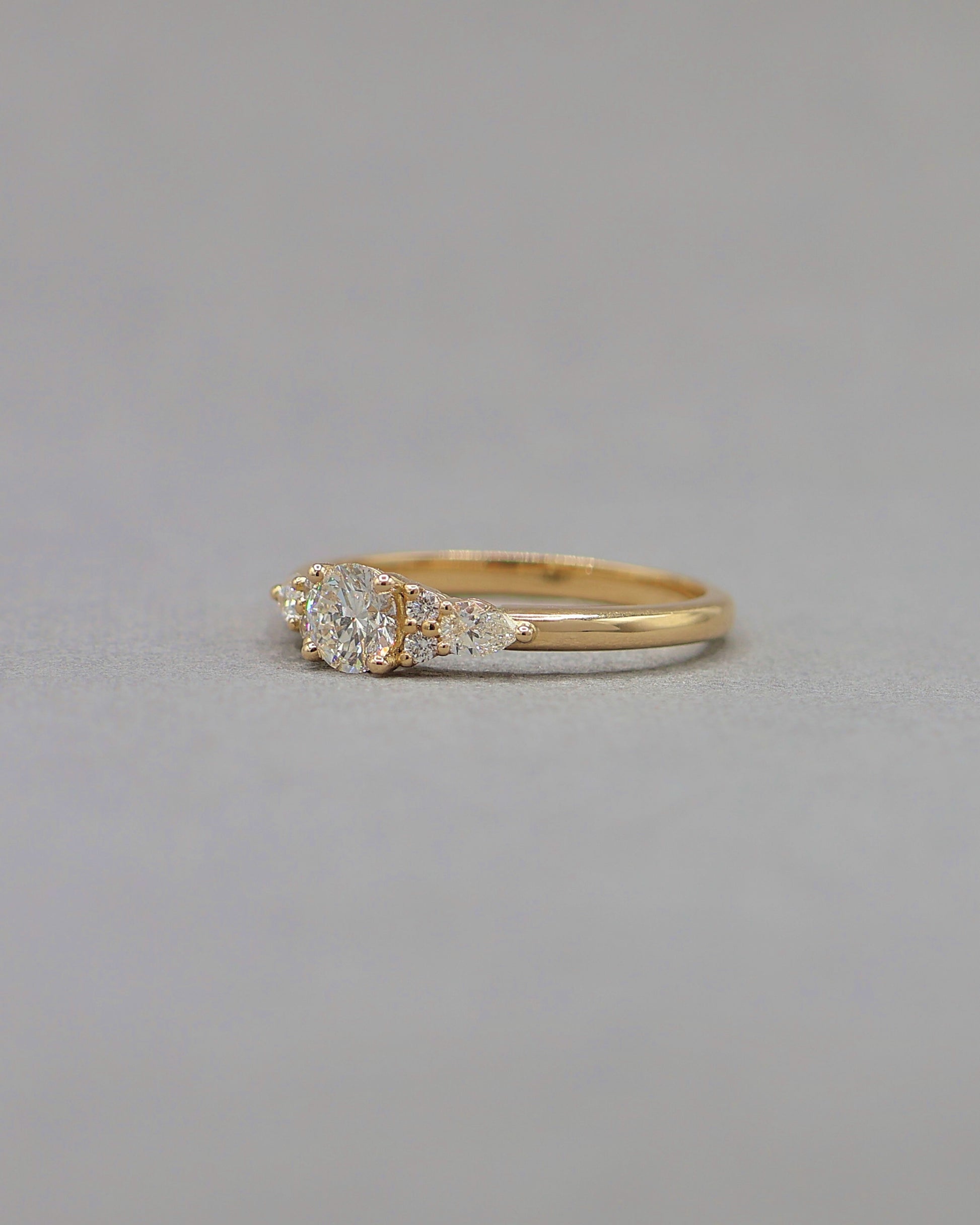 vue de cote d_une bague solitaire diamants epaule de diamants taille brillant et taille poire-bague de fiancailles en or jaune 18k