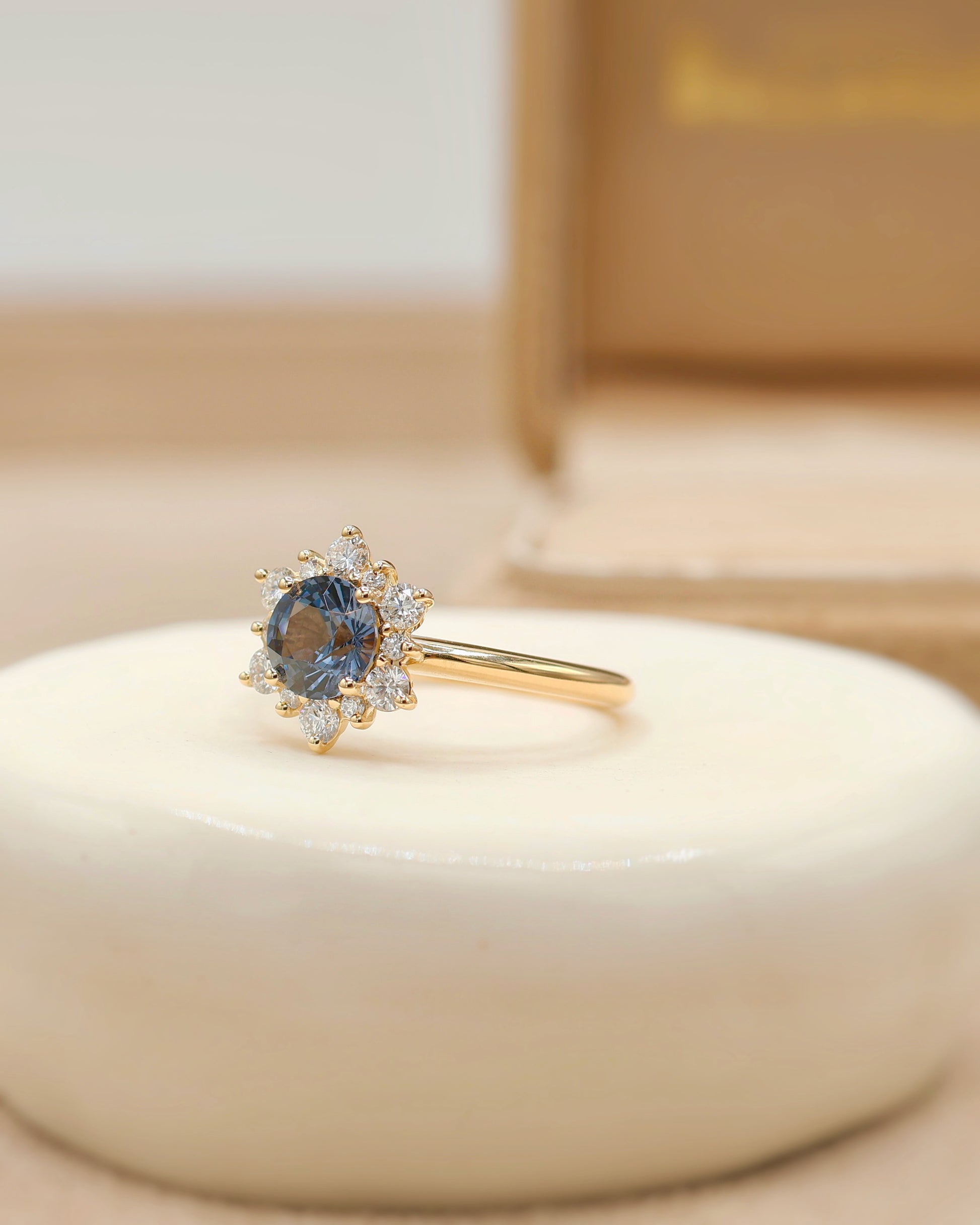 vue de coté bague de fiançailles avec un spinelle bleu et un entourage de diamants - bague marguerite en or jaune