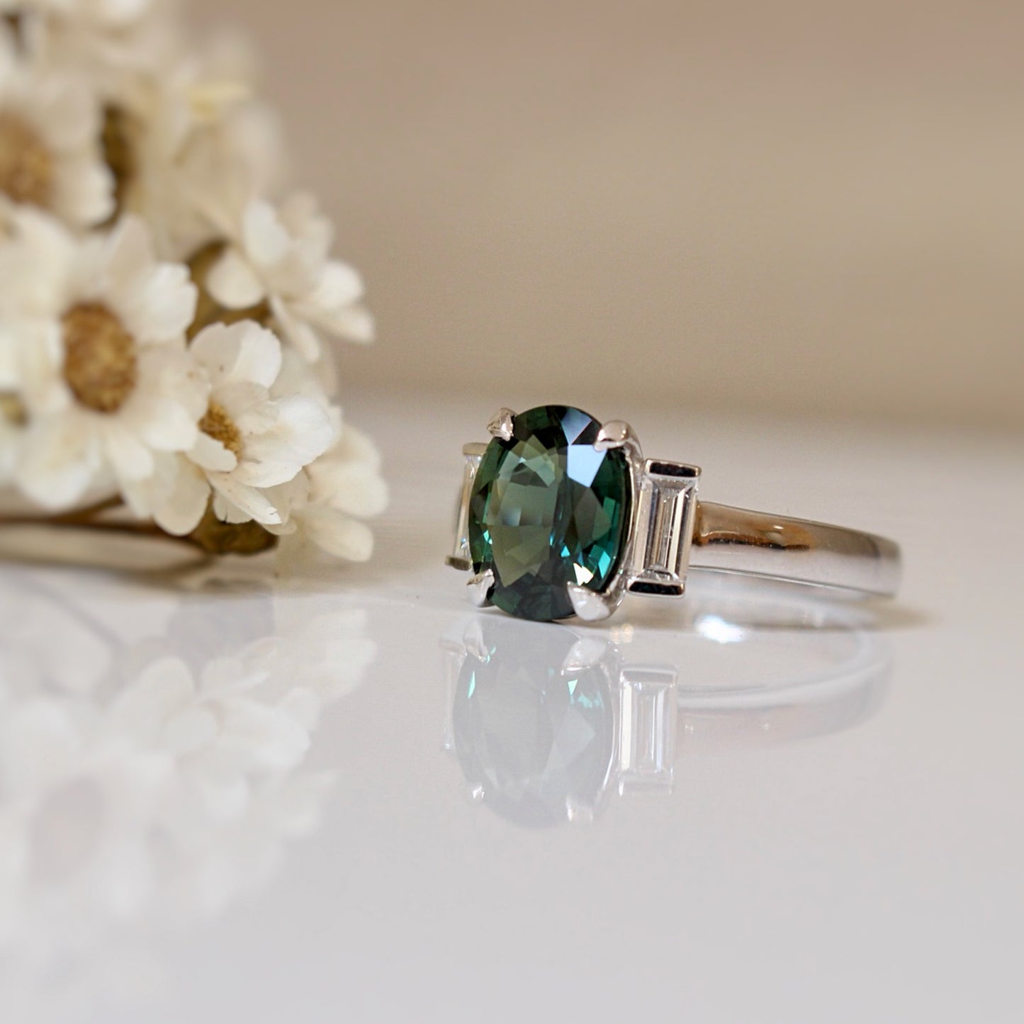 bague de fiançailles avec un superbe saphir vert foret épaulé de chaque côté par des diamants baguette