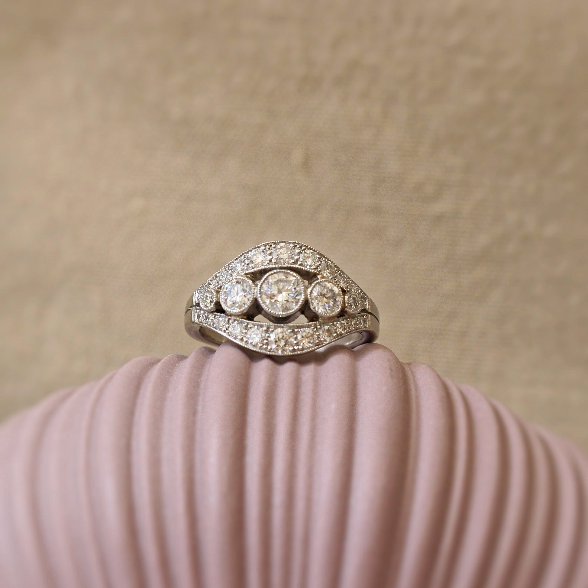 bague diamants formant 2 courbes qui viennent entourer une ligne de diamants en serti clos perlé/monture en platine