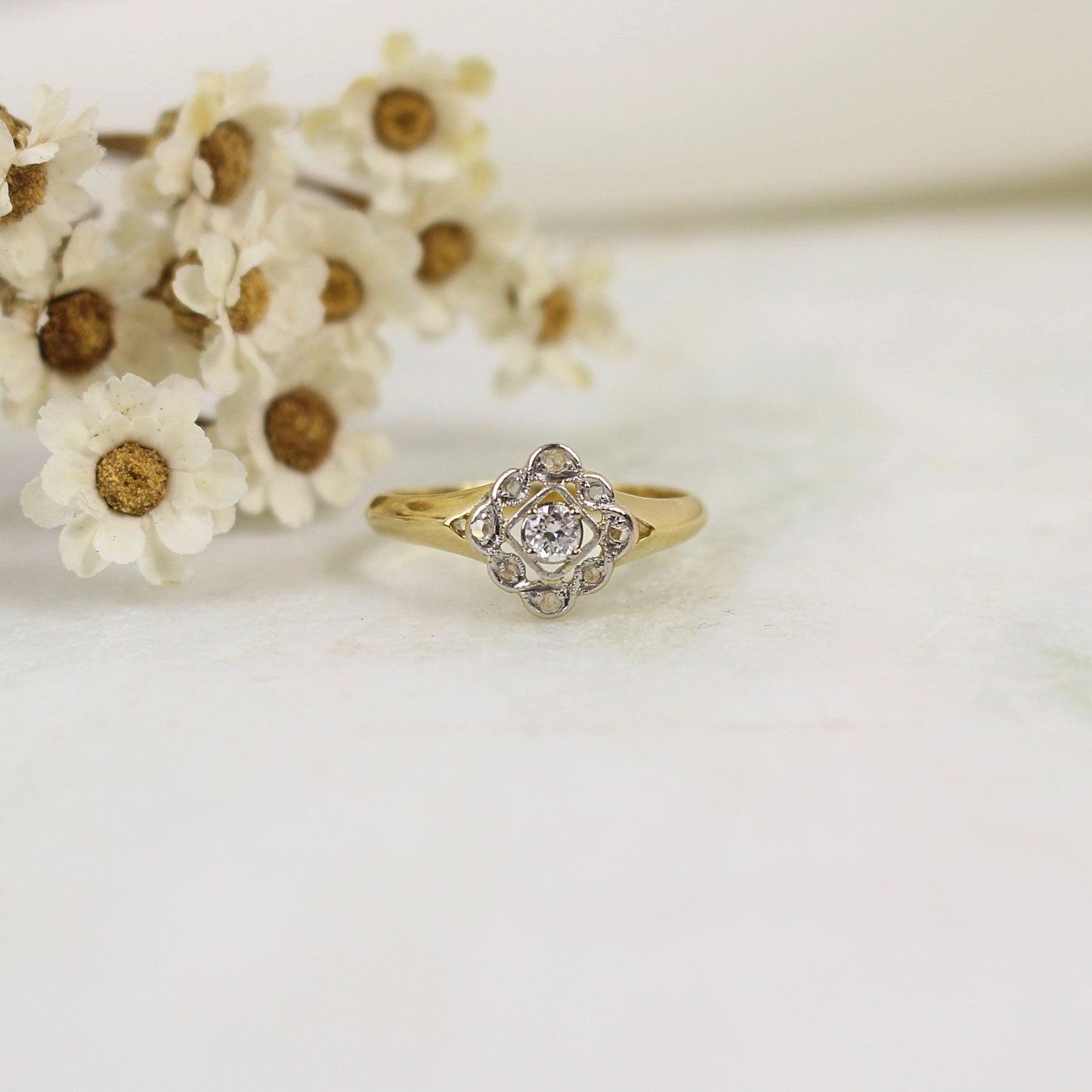 Très jolie bague losange esprit fleur avec un panier ajouré. Les pétales sont ornés de diamants taillés en rose et chaque pétale est entouré par un fil de platine filigrané.
