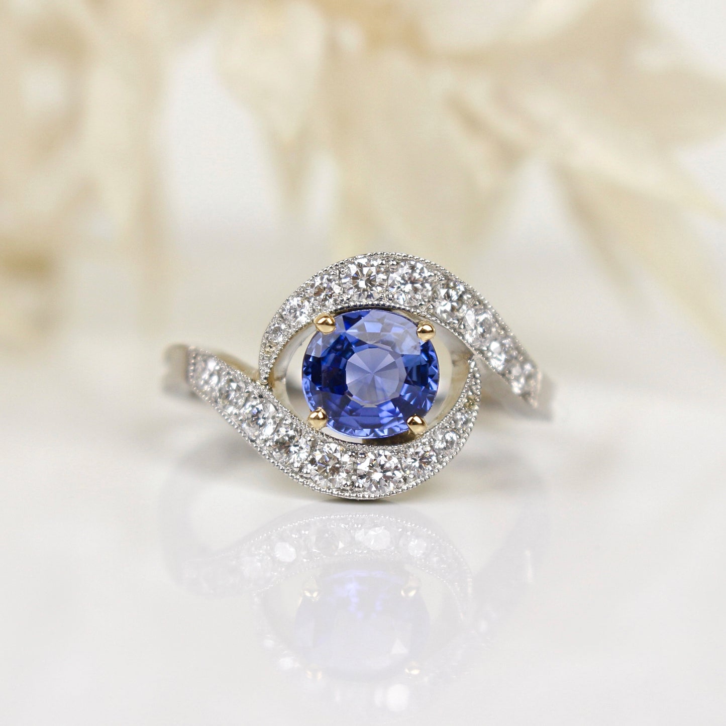 Bague toubillon avec au centre un saphir bleu taille ovale/volutes en diamants sertis grains/monture en platine