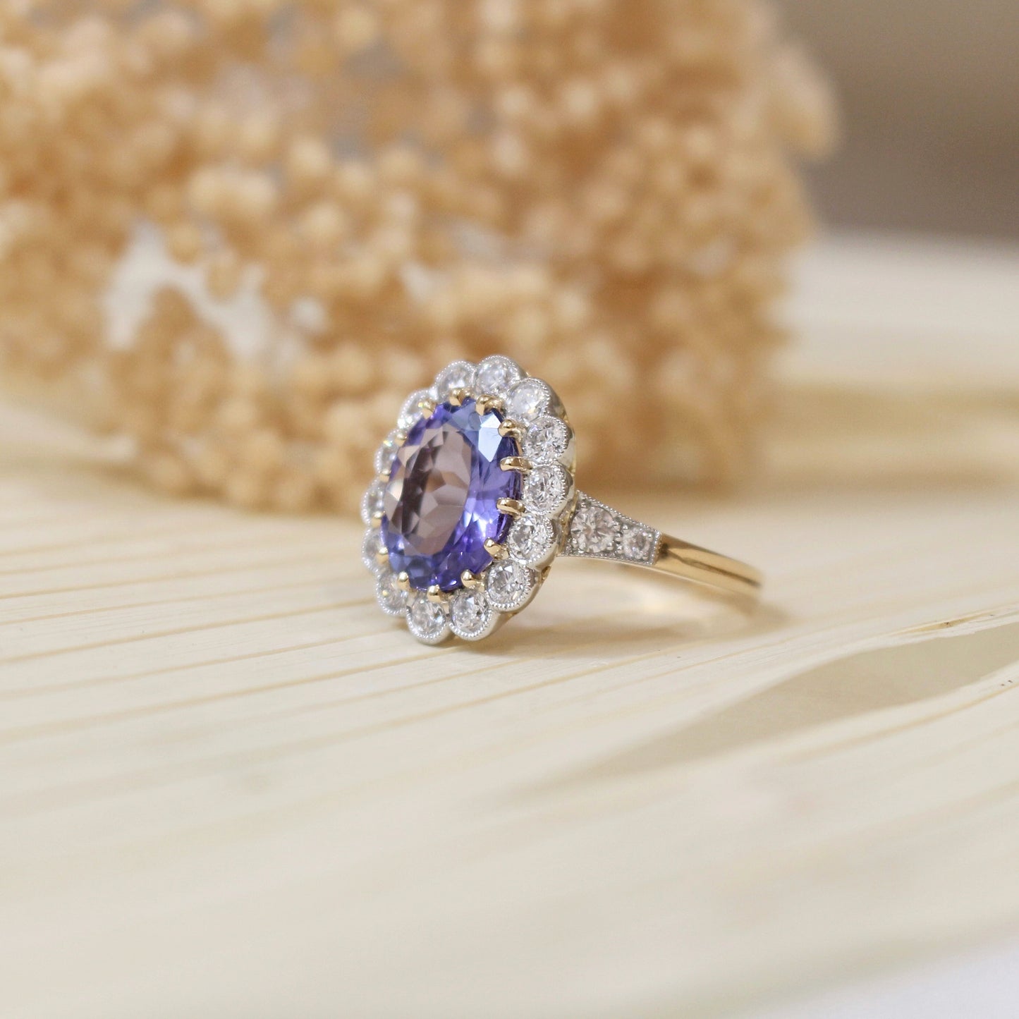 Volumineuse bague marguerite avec une tanzanite taille ovale et un entourage de diamants en serti clos perlé