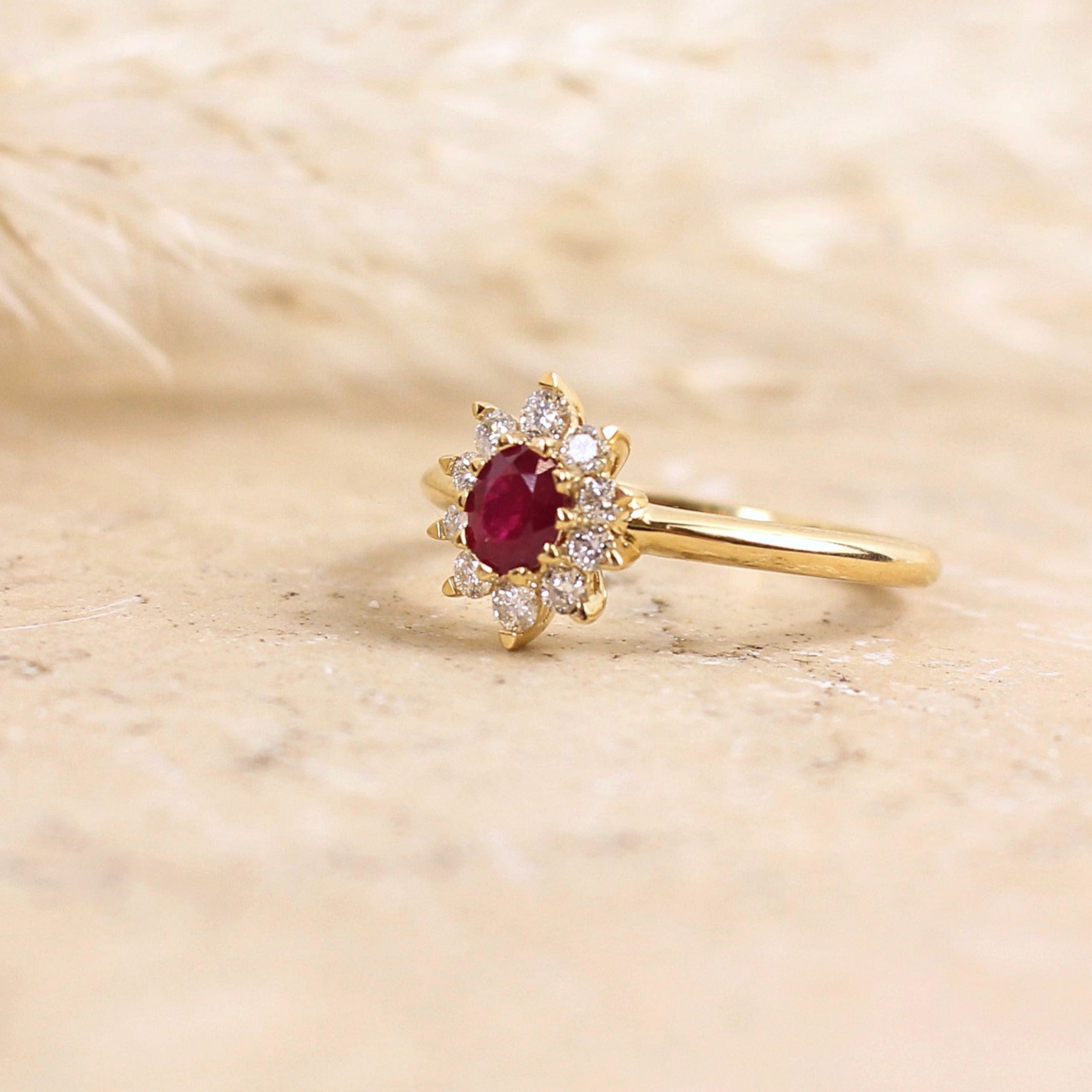 Jolie bague fleur, dite bague marguerite, ornée d'un rubis taille ovale entièrement entouré de diamants