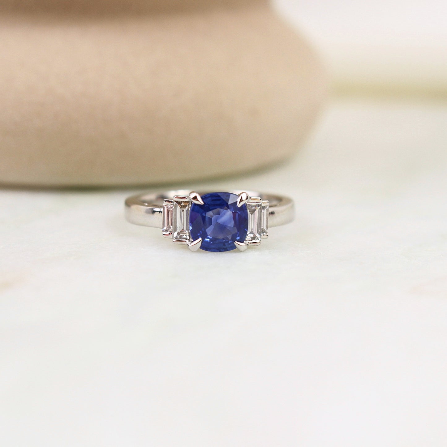 Bague saphir coussin épaulé par des diamants baguette en escalier. Très belles griffes de loup sur la pierre centrale 